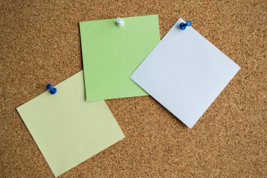 Beyaz bir raptiyeyle tutturulmuş, beyaz ve sarı renkli üç kağıt. Boşluğu kopyala.