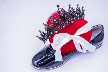 Kadın derisi ayakkabılar, kalp şeklinde ipek bir kutu ve beyaz arka planda bir taç..