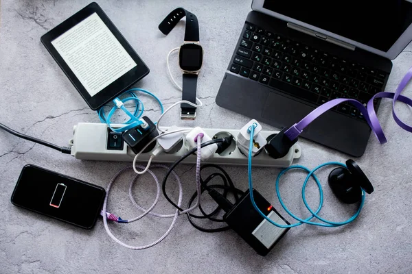 Moskova, Rusya, Ağustos 2020: Birçok cihaz - akıllı telefon, kablosuz kulaklık, dizüstü bilgisayar, akıllı saat, kamera aküsü ve e-kitap bir elektrik kablosuyla şarj ediliyor.