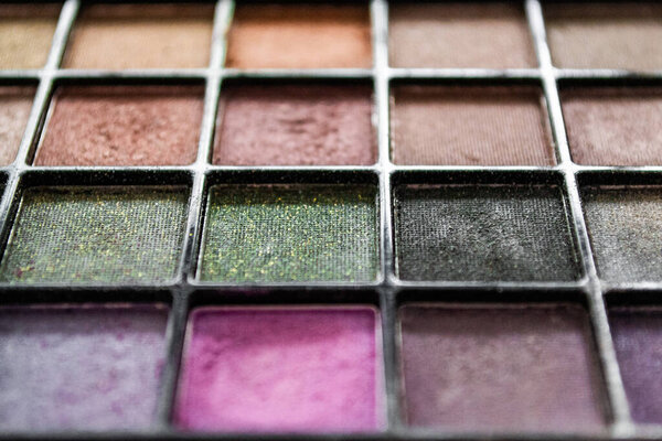 Close up palette with multi colored eye shadow. Makeup nude color, pink, black with golden shimmer.