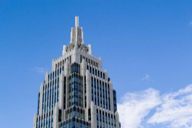 Bulutlu mavi gökyüzüne karşı bir ofis binasının işaret edilmiş kulesi. Boşluğu kopyala.