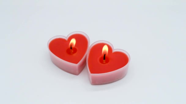 2本の鮮やかな赤のハート型のキャンドルが白い背景で燃えます 誕生日 バレンタインデーの概念 スペースのコピー — ストック動画
