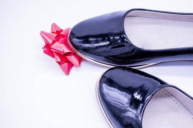 Kadınların siyah deri ayakkabıları, çiçek şeklinde kırmızı ipek bir fiyonka basılmıştı..