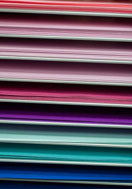 Pembe, kırmızı ve mor, turkuaz ve mavinin çeşitli tonlarında sanal renkli kağıt yığınları.