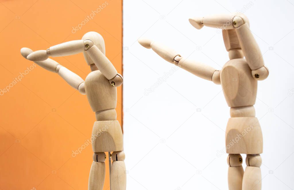 Two wooden human figures on white and orange backgrounds dance and make a deb movement - sneezing gesture.