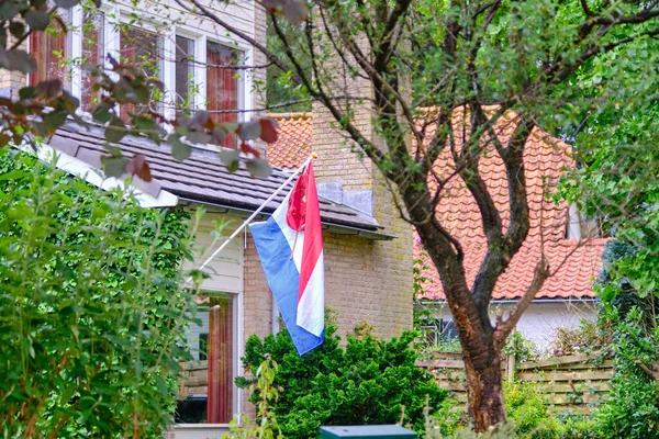 Nederlandse vlag in de regen met een tas, een schooltas, een traditie als een student afstudeert. Geen feest vanwege het Corona virus. Afstudeerdag 4 juni 2020 — Stockfoto