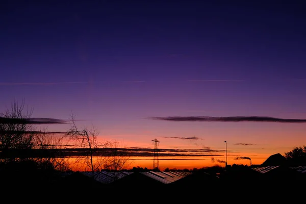 Colourful sunrise scenery above glasshouse with smoking chimneys and electricity pylons — Stock Photo, Image