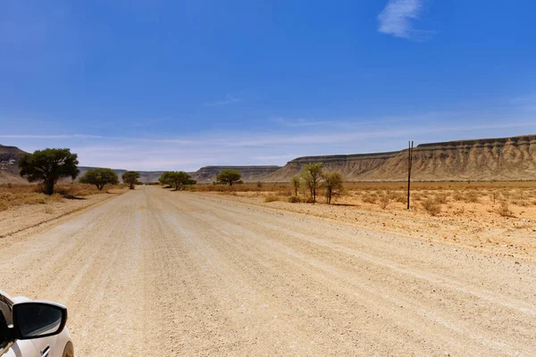 Afrika çölünde toprak yol manzarası ve sıcak bir yaz günü mavi gökyüzü ve araba aynası olan dağlar. Geniş ufuk
