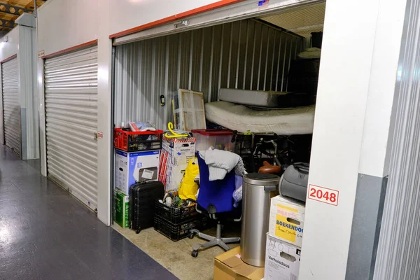 Bir depolama tesisinde açık kapısı ve ev eşyaları olan kapalı bir depo. Kiralık Depo Birimleri. Hollanda
