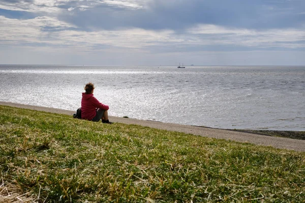 Harlingen, Hollanda, 23 Temmuz 2020: Wadden Denizi 'ne bakan bir hendekte genç bir kadının silueti. Corona krizi sırasında sorunları düşünmek, stres, güvensizlik, sevdiklerini kaybetmek, sosyal uzaklık