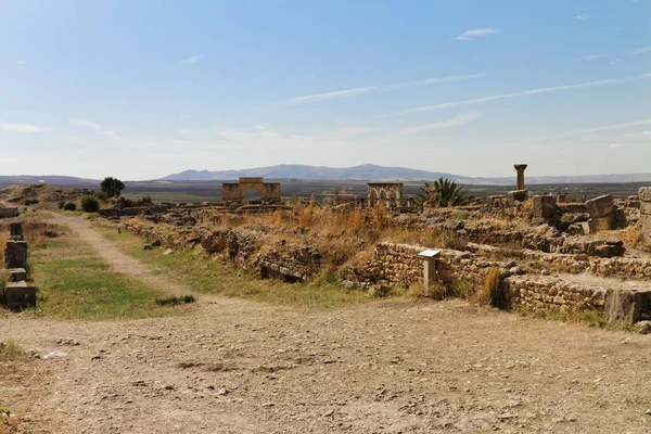 Volubilis manzarası, UNESCO 'nun Fas' taki dünya mirası sahası, Meknes kenti yakınlarında eski bir Berber şehrini kazdı. Zafer Kemeri, tarımsal alanlar ve arka planda dağlar. Mauretania Krallığı
