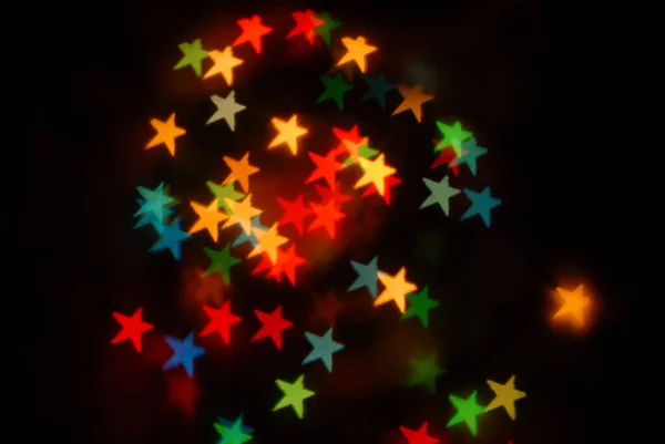 Bokeh estrellas luces de colores sobre fondo negro, Navidad — Foto de Stock