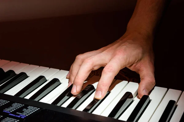 Müzisyen piyanonun anahtarlarıyla sentezleyicinin klavyesini çalar. Projektörlü bir konserde. — Stok fotoğraf