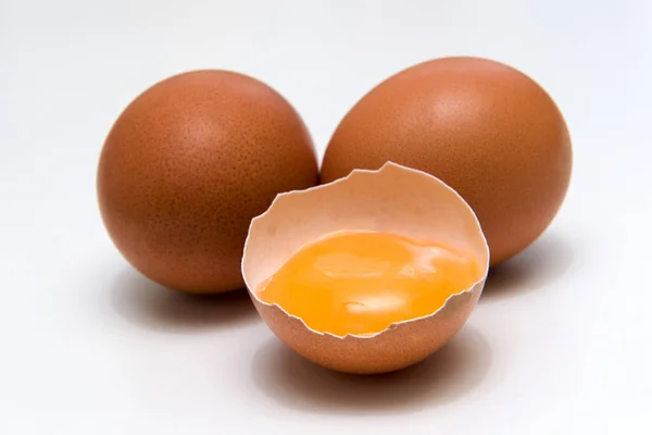 Tre uova, un uovo rotto, tuorlo d'uovo, isolato su fondo bianco — Foto Stock