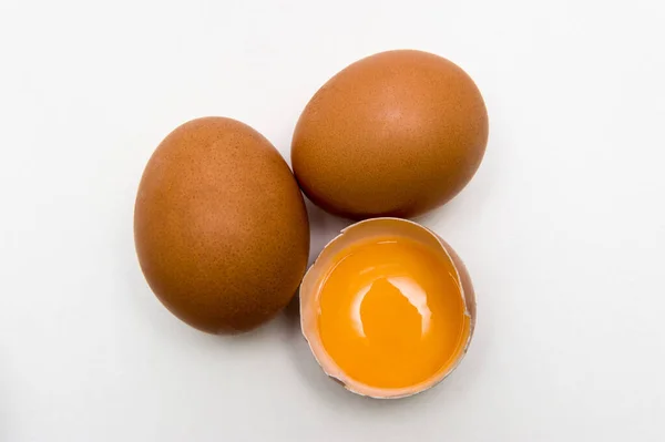 Tre uova, un uovo rotto, vista dall'alto, tuorlo d'uovo, isolato su fondo bianco — Foto Stock