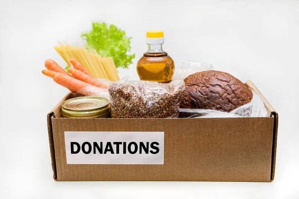 Cardboard box with food, food donation, home delivery, horizontal, copy space. Buckwheat, bread, pasta, canned food, butter, rice, onions, carrots. — Stock Photo, Image