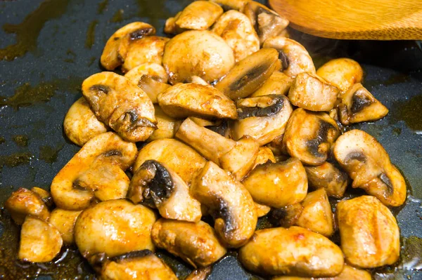 We cook mushrooms in a frying pan with oil. Close up.