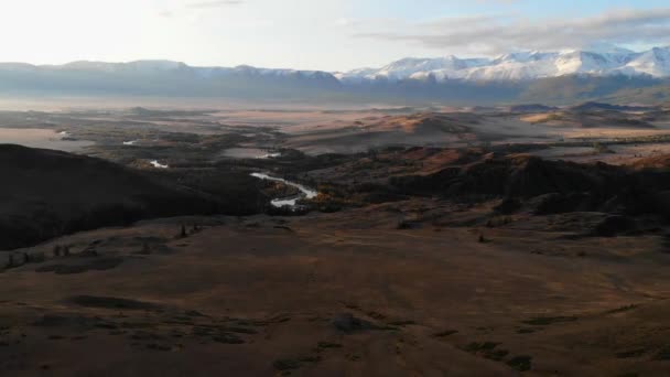 Bozkırın üzerinde bir kuadrokopter üzerinde uçan, dağların ve sonbahar ağaçlarının arka planında dönen bir nehir, Altai — Stok video
