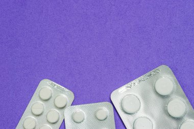 Mavi arka planda üç paket beyaz hap. Hastalıklar, eczacılık.