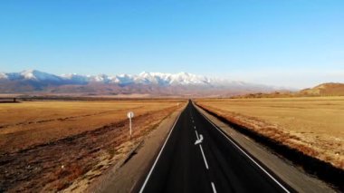 Sonbaharda, açık bir günde, bir karayolu üzerinde, dağların arka planına karşı bir kuadrokopter üzerinde uçmak, Altai
