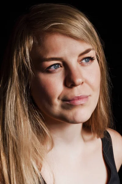 Una joven rubia hermosa con ojos azules en lentes ópticas y un aspecto reflexivo, un gran retrato sobre un fondo negro . — Foto de Stock