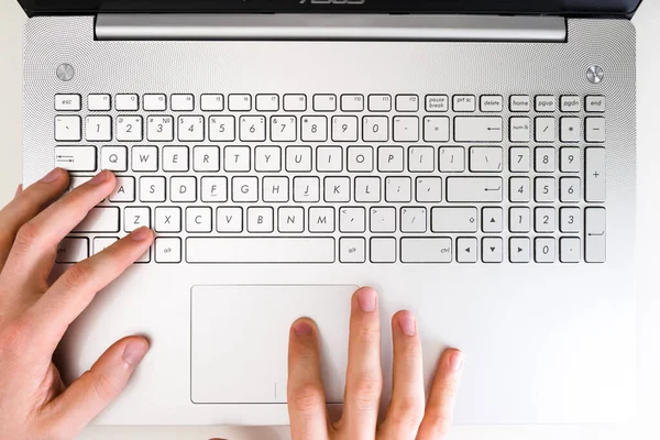 Desktop top view, male hands typing on the keyboard of a gray laptop, metallic. — Stock Photo, Image