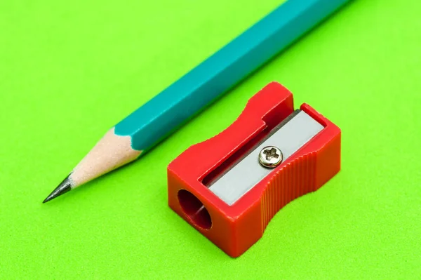 Zelený hrot tužky a červený ořezávátko leží na zeleném pozadí — Stock fotografie