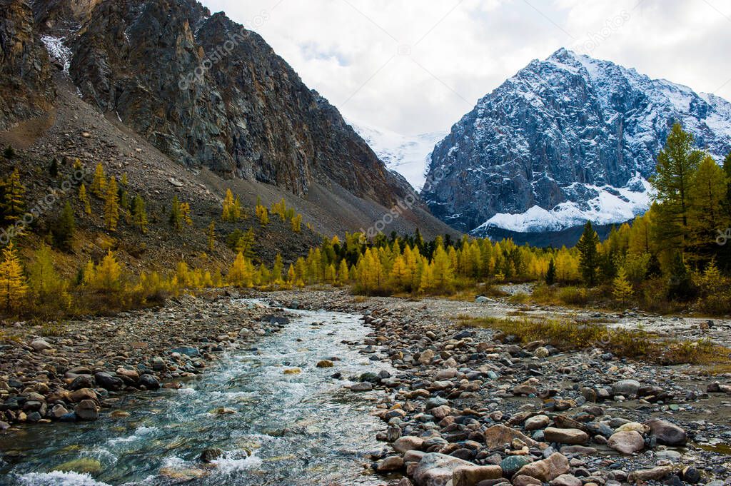 Autumn landscape with the Aktru river and Karatash peak. Altai mountains in cloudy weather. Siberia. Russia