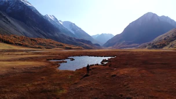 Dron odletí od jezera a nabere výšku, na pozadí hor a žlutých stromů, Altai. — Stock video