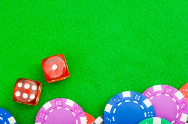 Yakın plan poker fişi ve iki kırmızı zar fotokopi alanı olan yeşil kumaş bir masa üzerinde..