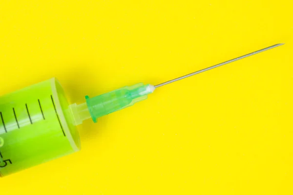 Jeringa médica con aguja afilada sobre fondo amarillo — Foto de Stock