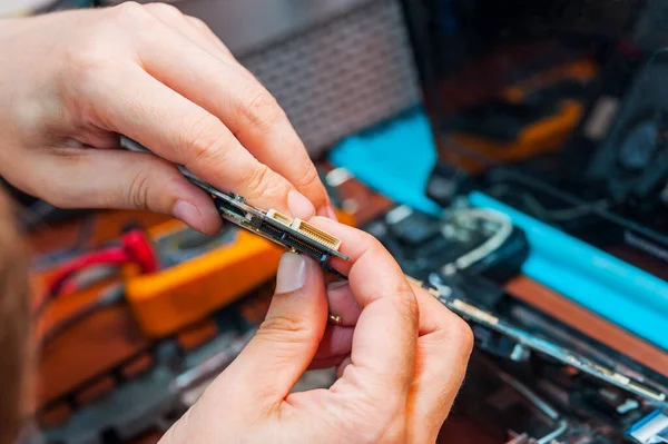 Un administrador de sistemas profesional tiene las tomas de corriente en sus manos. Un hombre repara y construye una computadora . — Foto de Stock