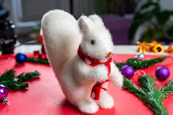 Christmas toy white squirrel on a red background in a red scarf with Christmas entourage — Stock Photo, Image