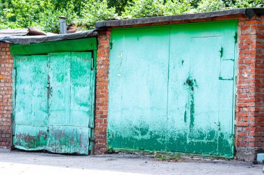 Demir kapılı ve yeşil boyalı iki eski monolitik garaj.