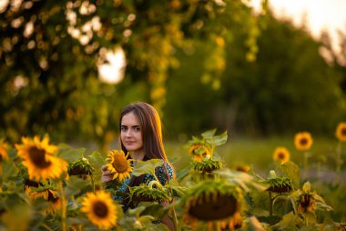 Bir çiçeğin önünde duran biri.