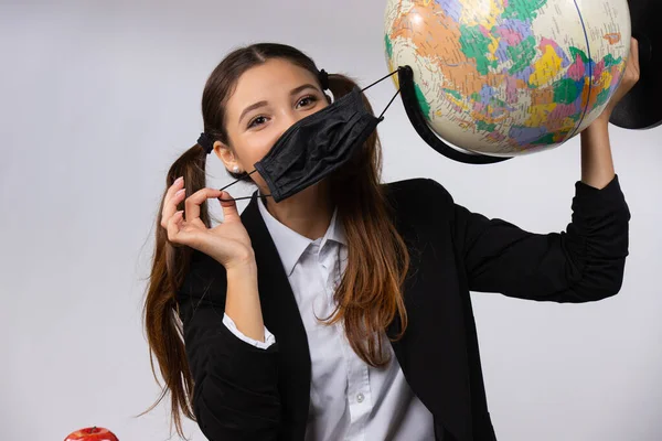Dziewczyna trzymała w ręku maskę i kulę. Koncepcja zanieczyszczenia powietrza i środowiska przez działalność człowieka. Podróże pandemiczne — Zdjęcie stockowe