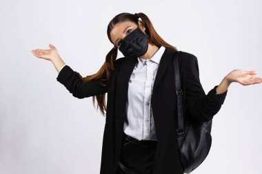Yüz maskeli iyimser Avrupalı esmer kız boş elleri gösteriyor