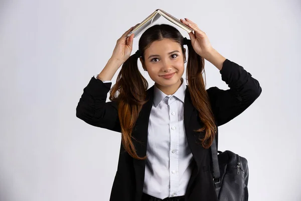 Foto retrato de chica morena sosteniendo libro abierto sobre la cabeza aislado sobre fondo blanco —  Fotos de Stock