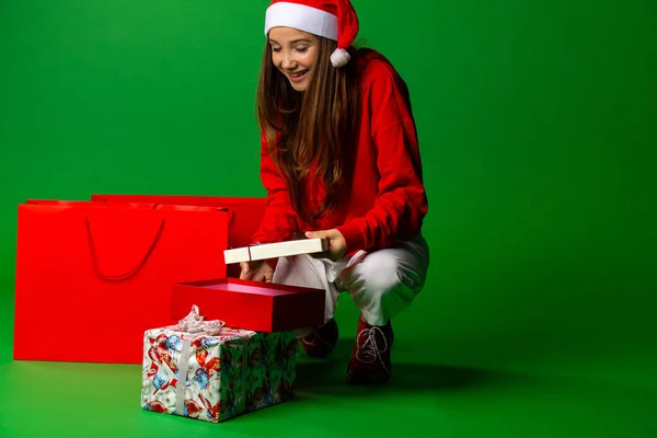 Портрет счастливой улыбающейся девушки, открывающей подарочную коробку на зеленом фоне — стоковое фото