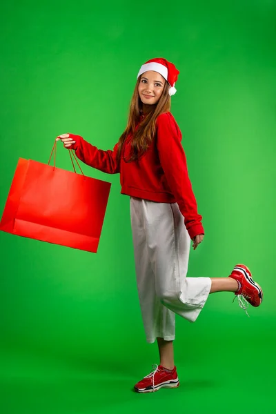 Mujer hermosa y morena en ropa roja y blanca con bolsa aislada sobre fondo verde — Foto de Stock