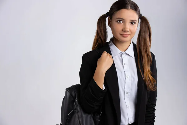 Estudiante de uniforme. Feliz sonrisa en el fondo blanco. Hermosa joven linda chica caucásica con mochila negra —  Fotos de Stock