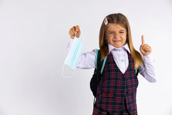 Foto de niña de la escuela pequeña escuela de ropa escolar no les gustan las reglas epidémicas no quieren usar máscara facial . — Foto de Stock