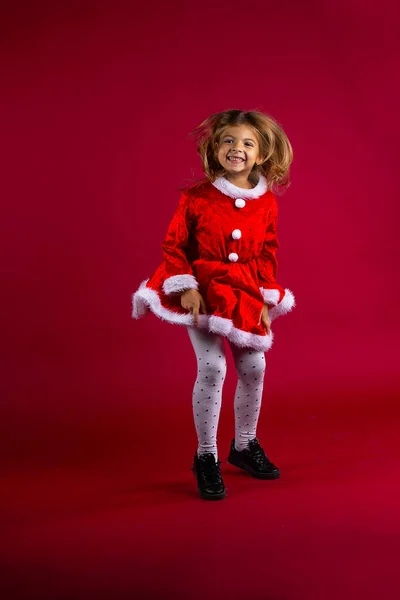 Feliz chica divertida en traje de Navidad rojo saltar sobre fondo de color rojo cereza — Foto de Stock