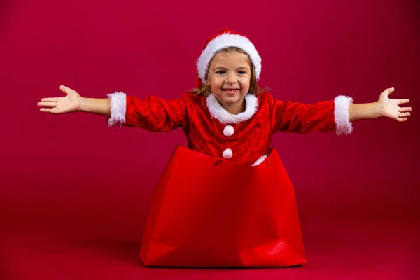 Chica caucásica escapar del paquete rojo regalo. Sorpresa con las manos abiertas. Feliz Año Nuevo. Fondo rojo, alta calidad — Foto de Stock