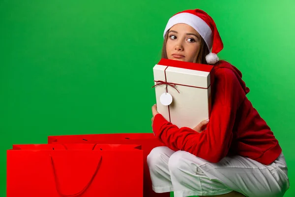 Грустная девушка рядом рождественские сумки глядя в сторону, изолированные на зеленом фоне — стоковое фото