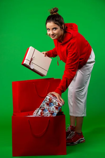 Брюнетка смотрит в камеру, кладет упакованные подарки в сумки, подготовленные к празднованию Рождества и Нового года — стоковое фото