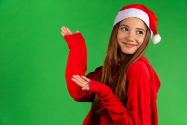 Güzel bayan Noel Baba 'nın yakından çekilmiş portresi dans ediyor ve dışarı bakıyor, yeşil arka planda izole edilmiş.