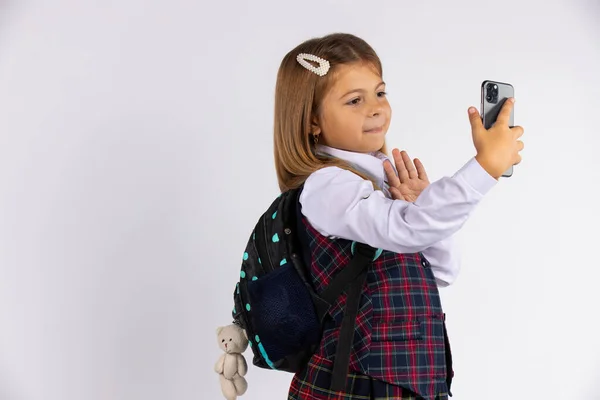 Foto av glada vackra blondine skolflicka tar selfie på mobiltelefon och gester halloskylt isolerad på vit bakgrund med ledigt utrymme — Stockfoto