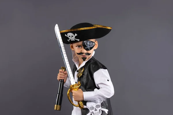 Classic captain pirate with face painted lunging forward with raised sword in challenging pose. Isolated on gray background with plenty of room for copy. Happy Halloween