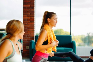 Omuzlarında havluyla sportif bir kız. Spor salonundaki bir fitness modelinin fotoğrafı, dinlenme zamanı.. Spor ve sağlıklı yaşam tarzı kavramı